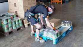 Un operario, con un exoesqueleto, carga peso en un almacén logístico.