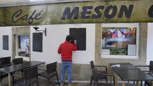 Un hombre escribe en la pizarra de un mesón, en Santiago de Compostela.