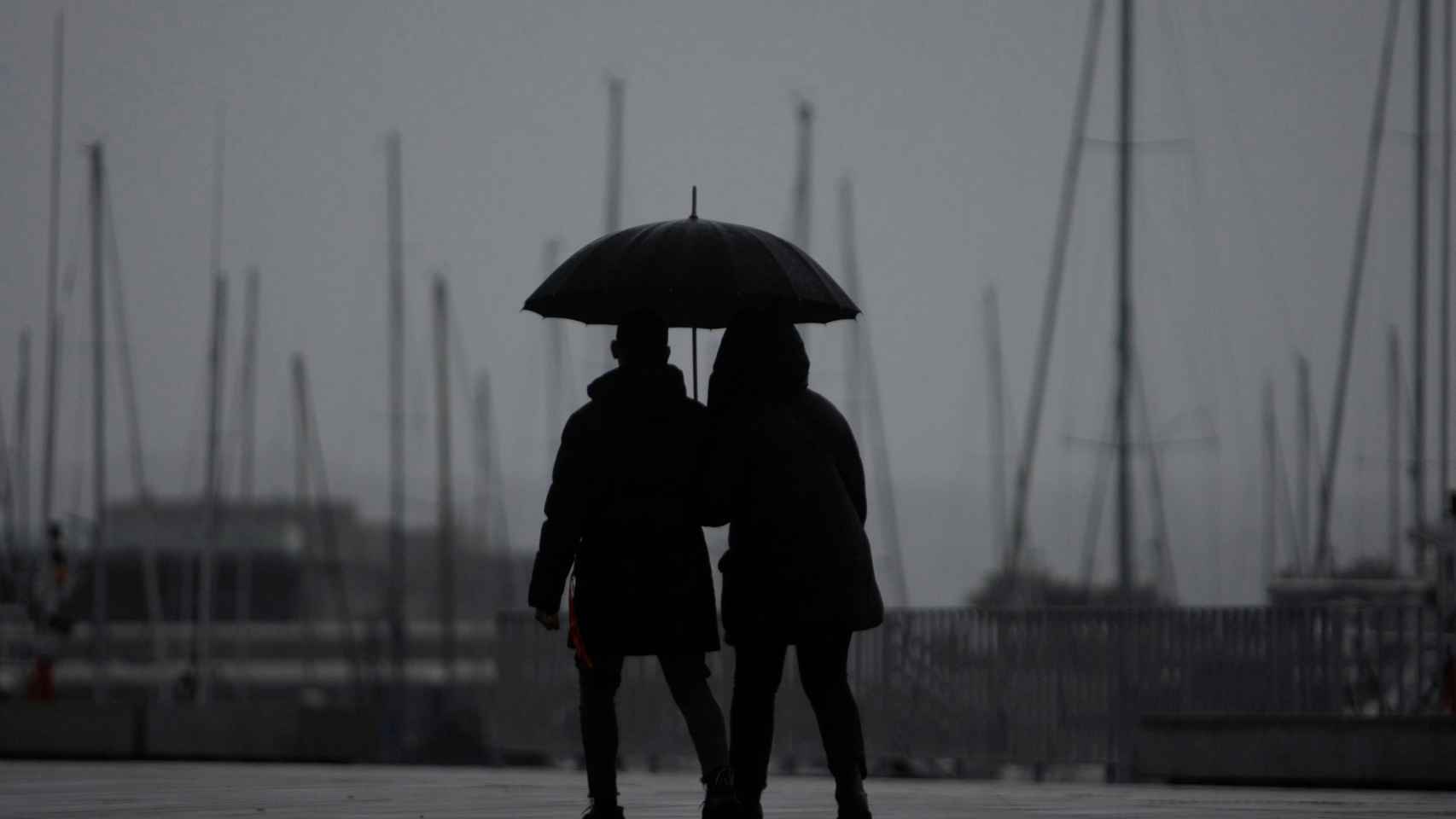 Dos jóvenes pasean bajo la lluvia.