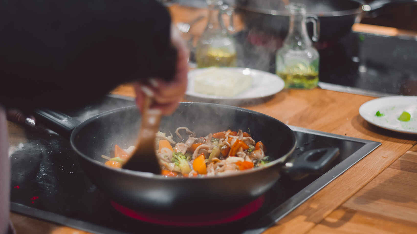 Una persona cocina verduras en una sartén.