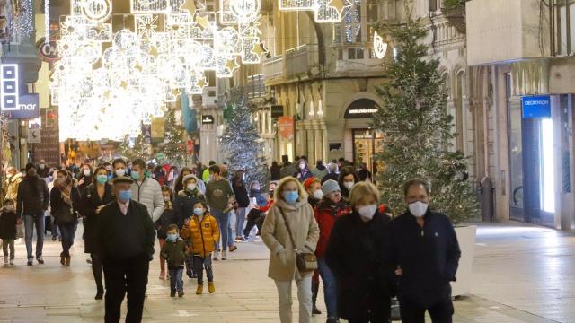 Transeúntes pasean bajo las luces navideñas.