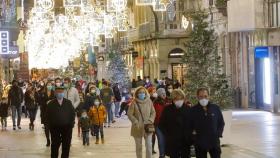 Transeúntes pasean bajo las luces navideñas.