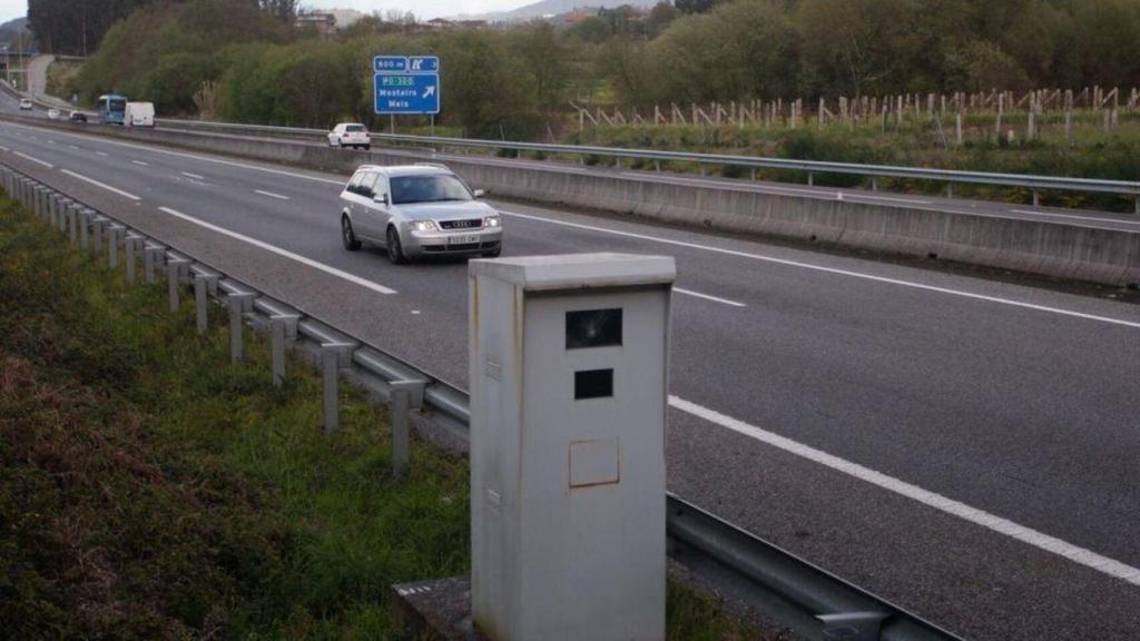 Un coche, en un autovía, pasando al lado de un radar de velocidad de la DGT.