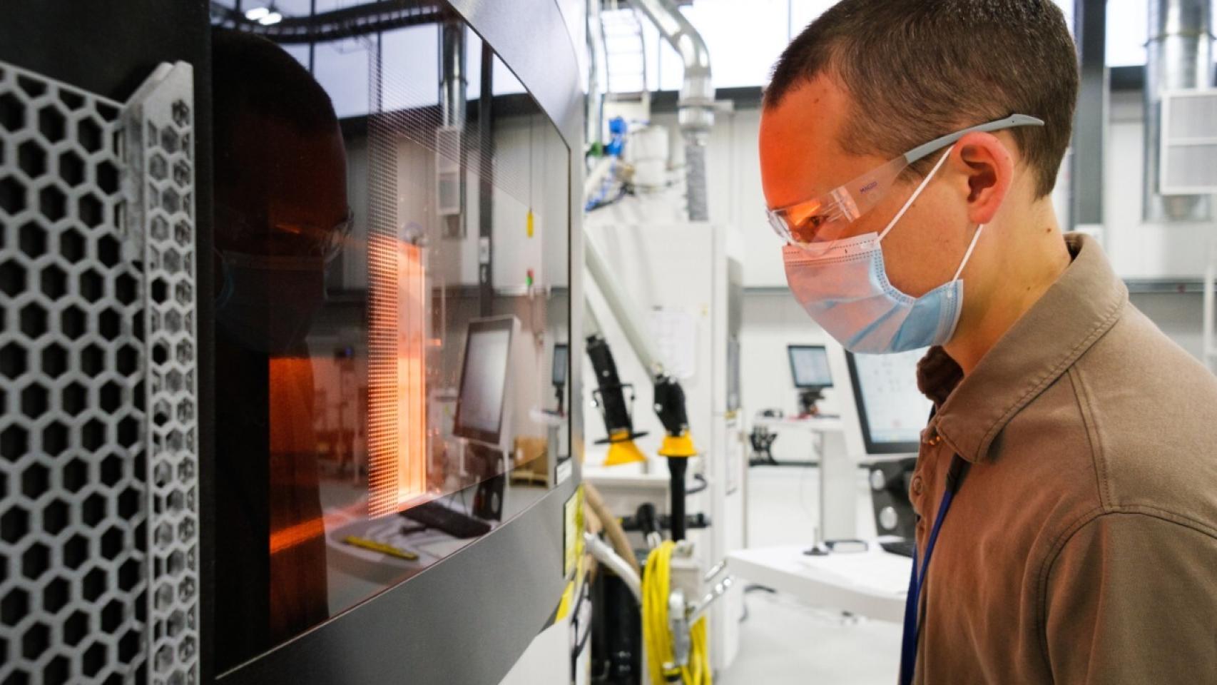 El ingeniero de General Motors Benjamin LeBlanc inspecciona una impresora 3D en el centro de fabricación aditiva.