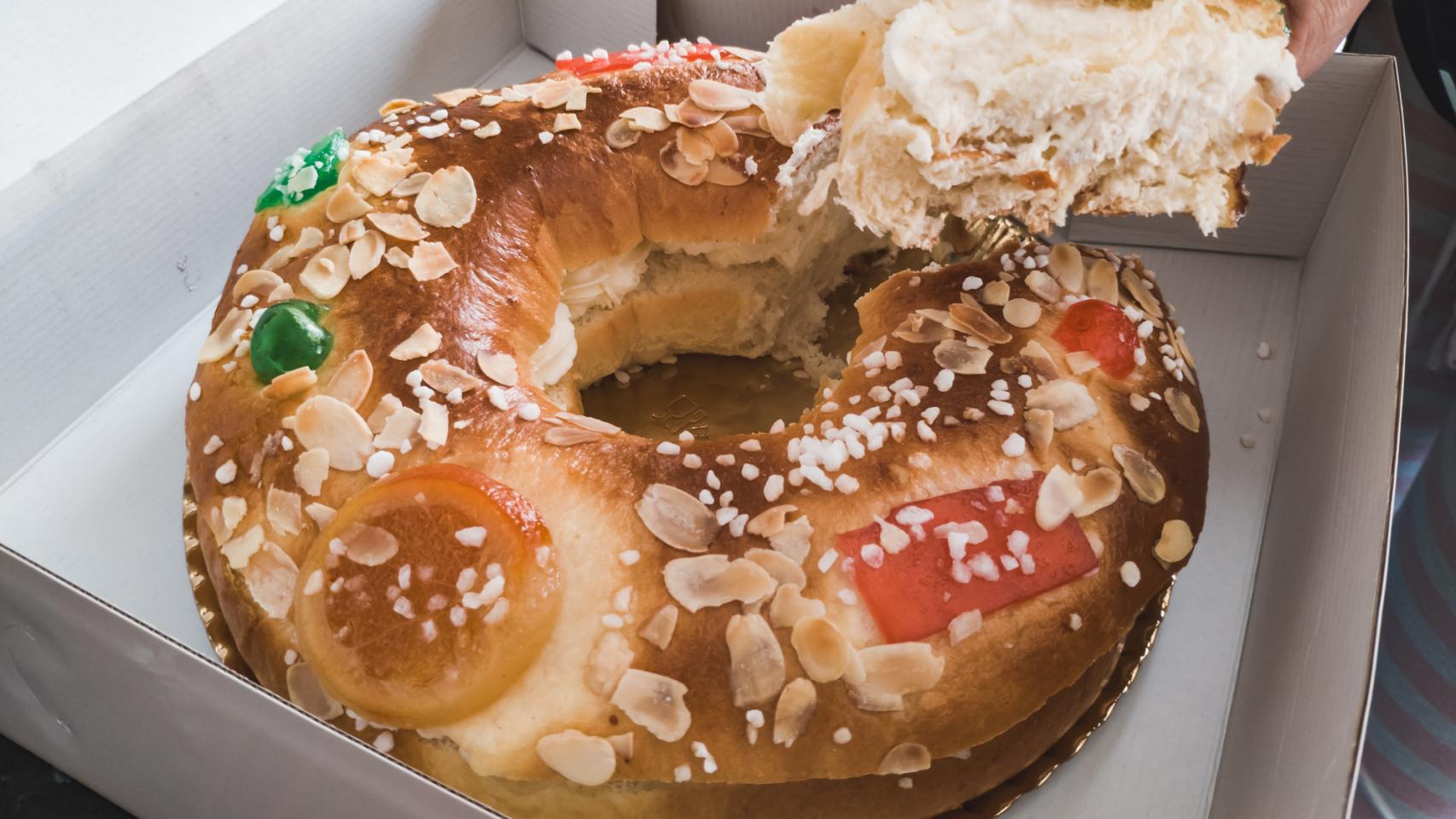 Una persona coge un trozo de roscón relleno de una caja.