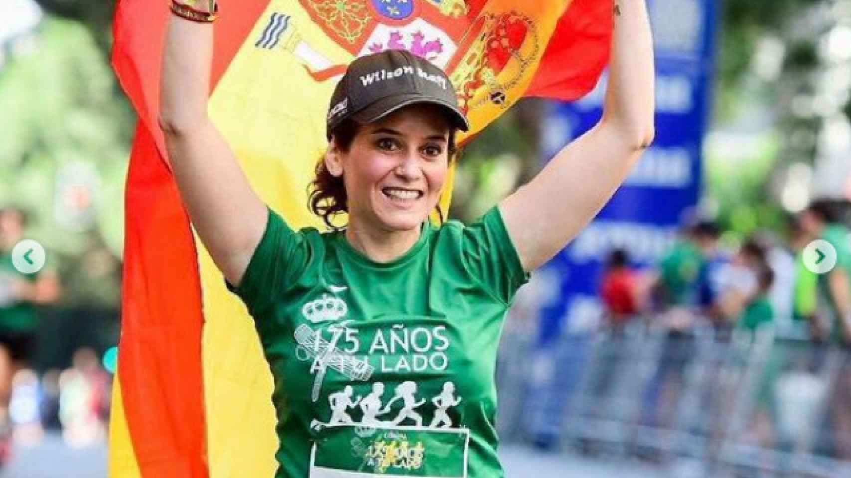 Isabel Díaz Ayuso porta la bandera de España mientras participa en una carrera.