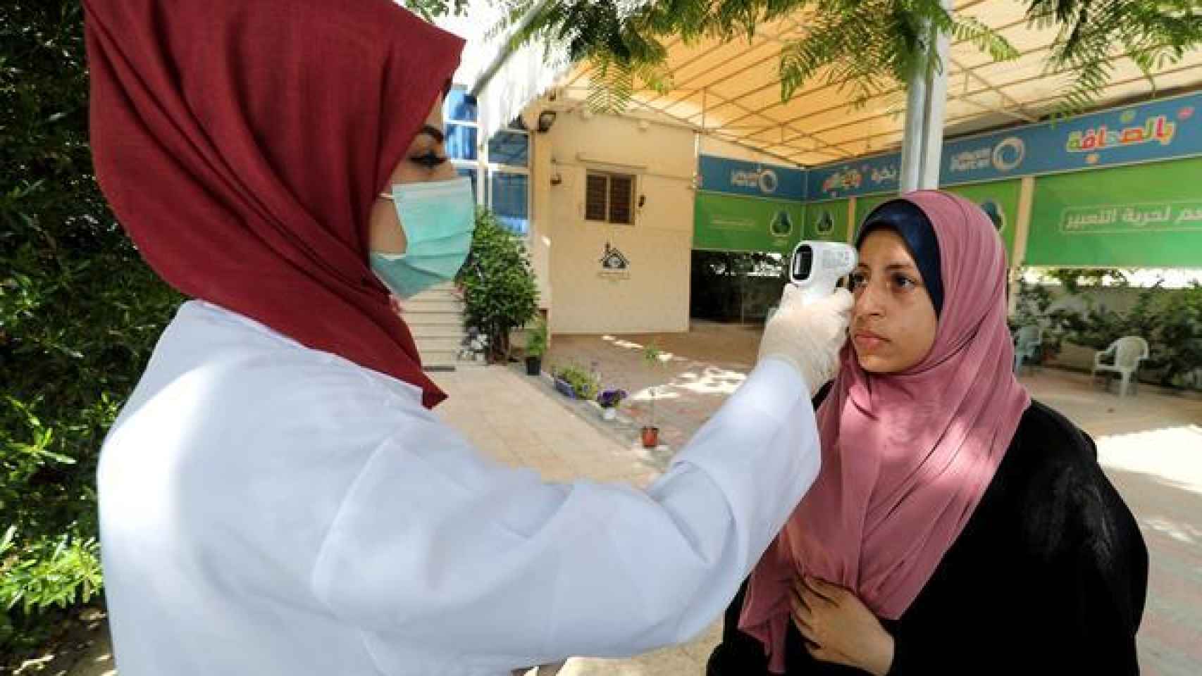 Una trabajadora sanitaria le toma la temperatura a una mujer palestina en Gaza.
