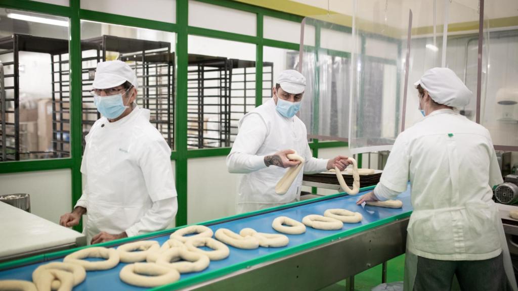 Varios pasteleros dan forma a los roscones de Reyes.