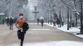 Un hombre corre por El Retiro de Madrid durante la nevada de este jueves.