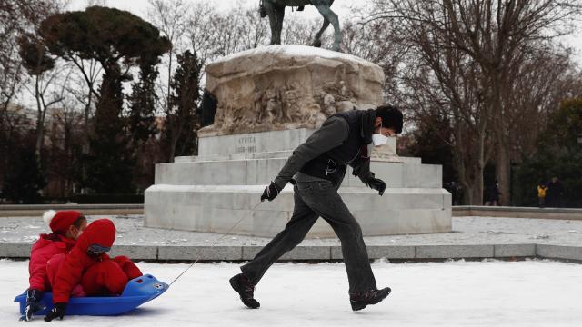 Un hombre este viernes tira de un trineo con niños en el parque del Retiro.