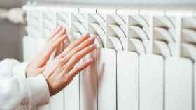 Una persona calienta sus manos en un radiador