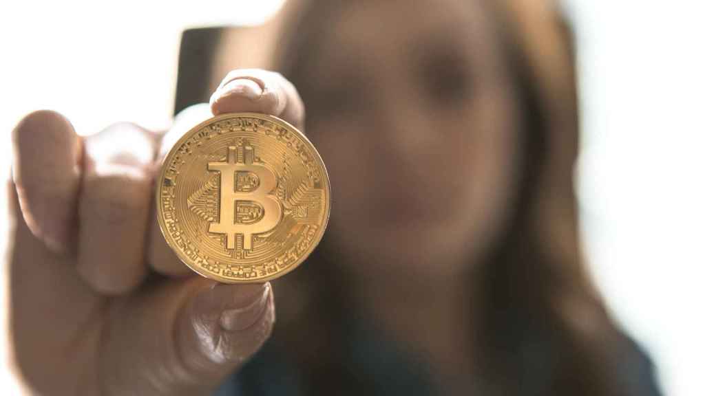 Un inversor sostiene una moneda física de bitcoin.