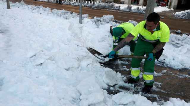Unos operarios retiran nieve acumulada este lunes en la plaza de Colón de Madrid.