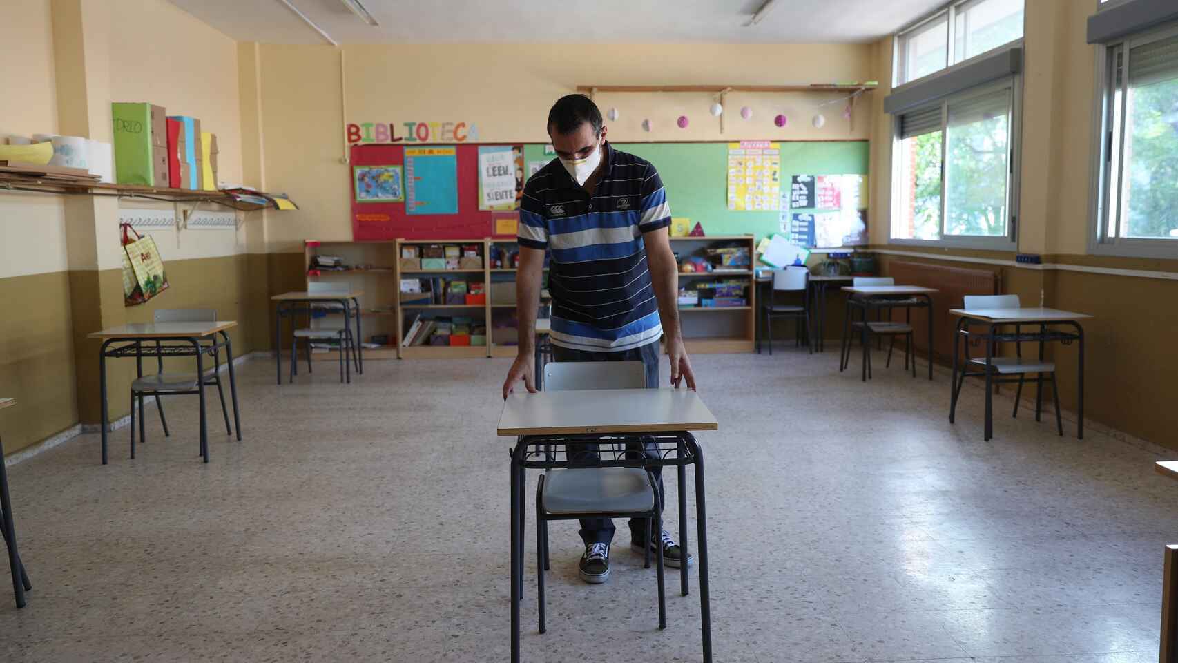 Un profesor separa las distintas mesas de sus clases.