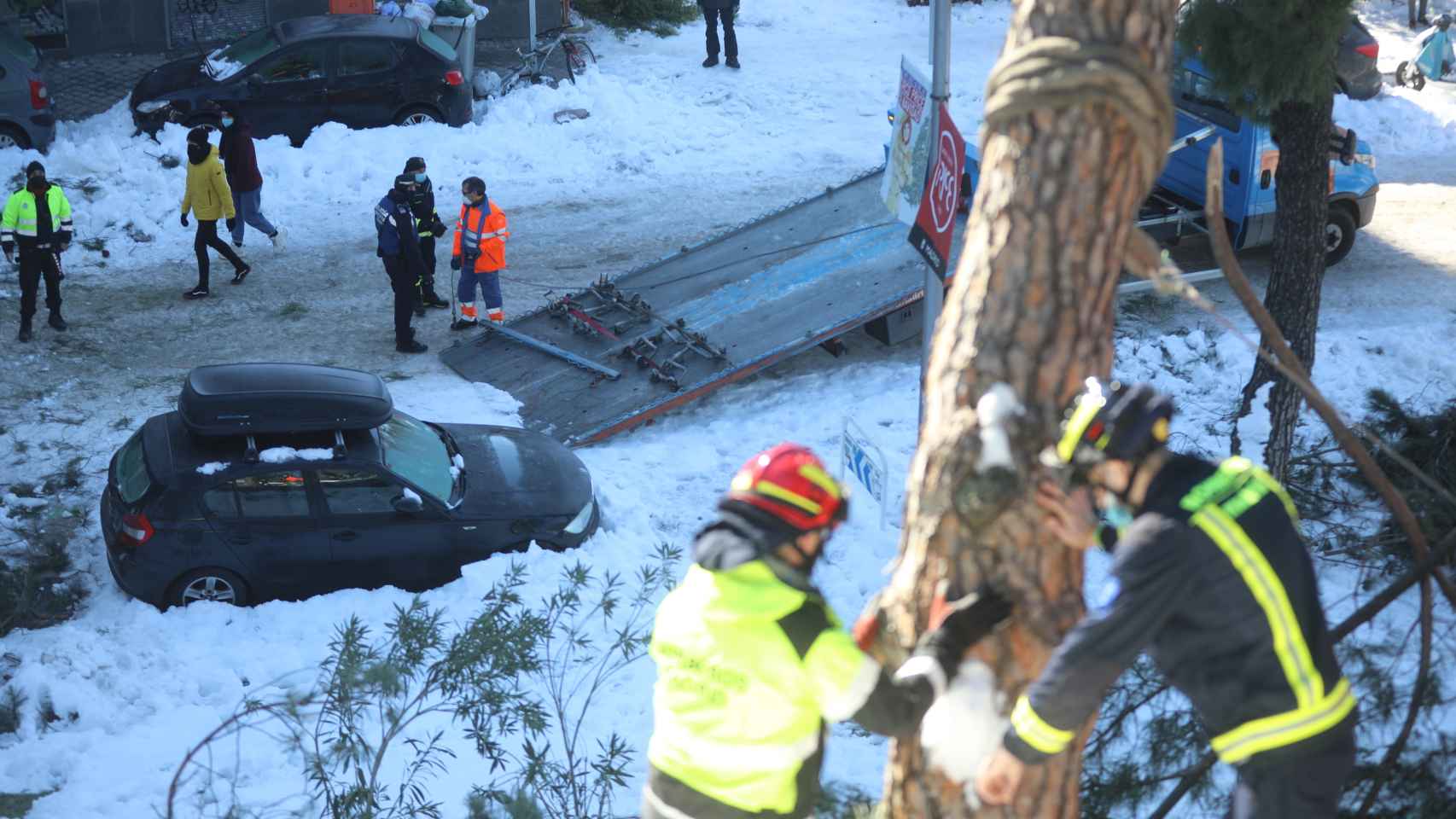 Una grúa del Ayuntamiento saca un coche y dos trabajadores municipales retiran un árbol tras la borrasca.