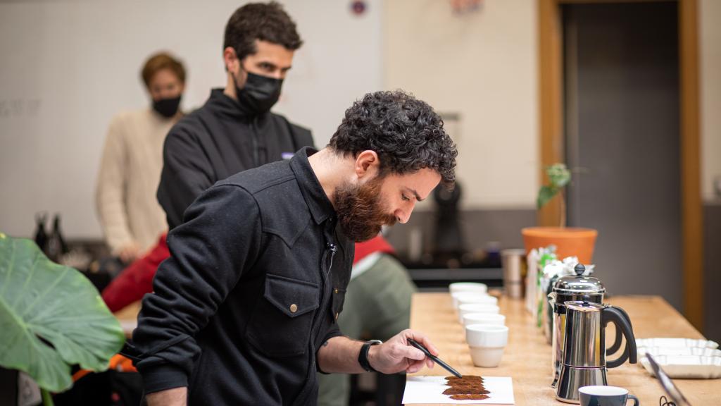 El maestro tostador Nolo inspecciona las muestras de los seis cafés molidos naturales, mientras el barista Pablo observa.