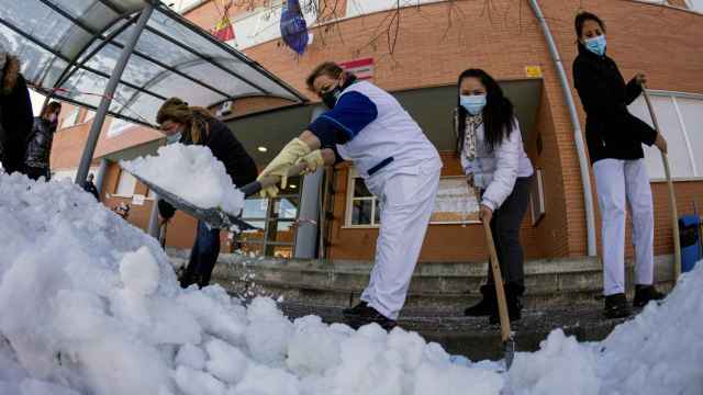 Personal de limpieza, junto a madres y padres, retiran hielo y nieve en el colegio Angel León, Colmenar Viejo, Madrid.