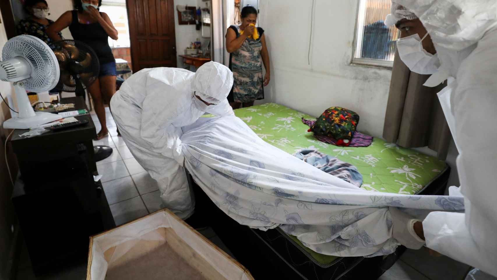 Trabajadores de una funeraria de Manaos retiran el cuerpo de una persona fallecida en su casa.