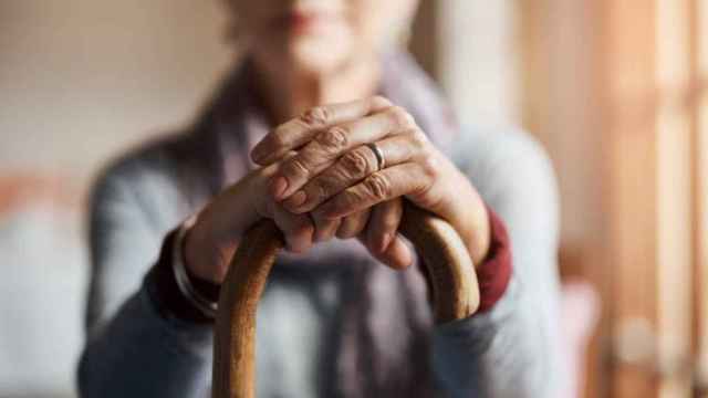 Una paciente con alzhéimer apoya sus manos sobre un bastón.