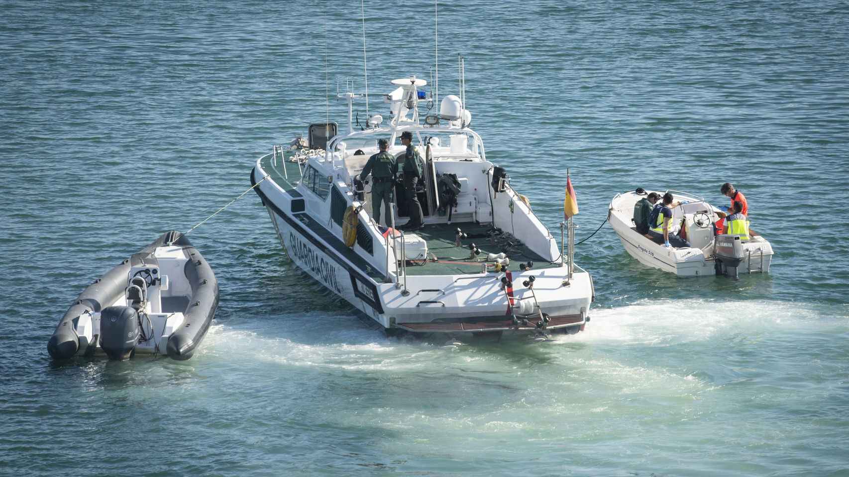 Una patrullera de la Guardia Civil traslada hasta el puerto de Algeciras la lancha (i) y la barca en la que navegaban el menor fallecido y su padre, el 14 de mayo de 2018.