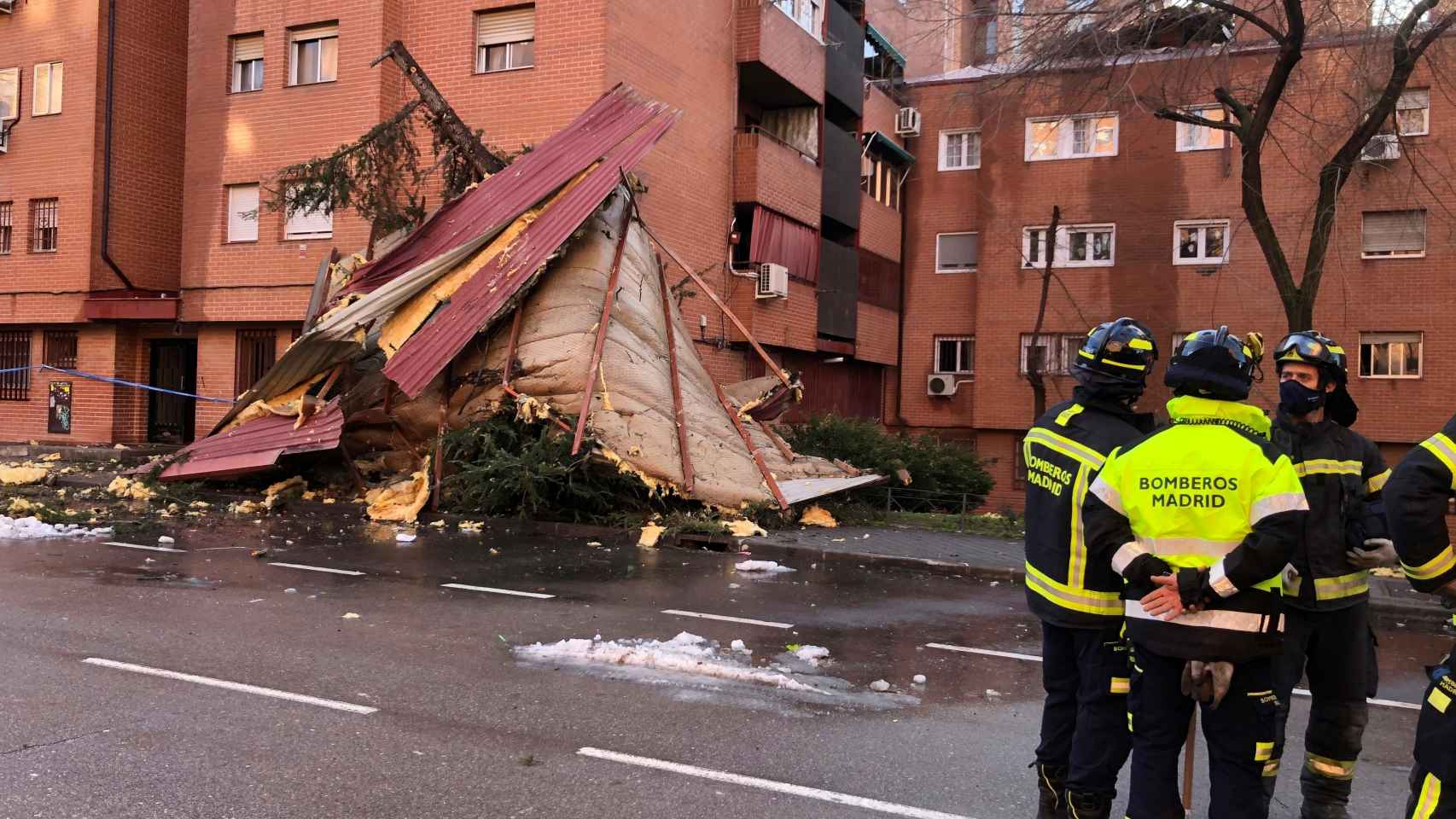 Efectivos del Cuerpo de Bomberos de Madrid intervienen este viernes en la caída de dos faldones de cubierta por el fuerte viento.