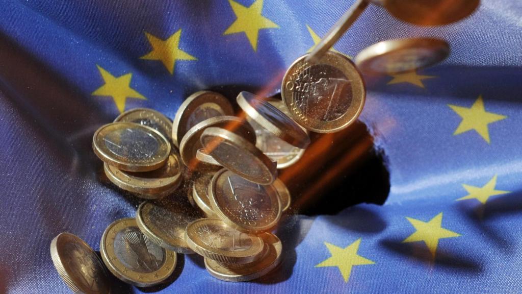 Monedas de euro sobre una bandera de la Unión Europea.