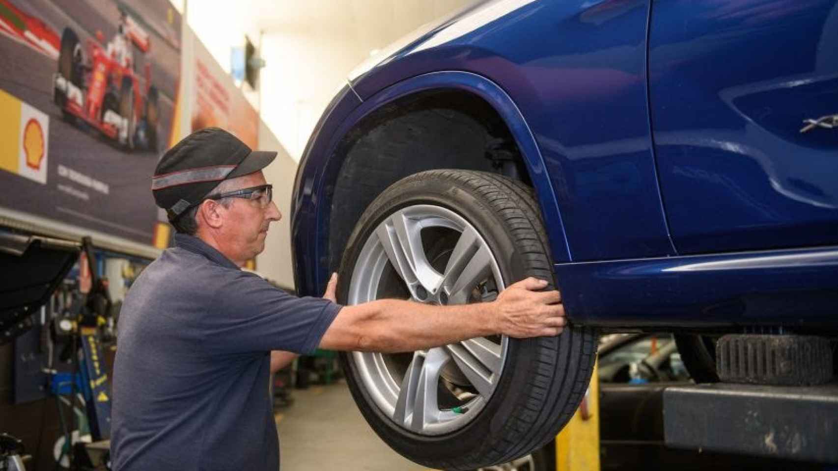 Un mecánico cambiando la rueda de un coche.