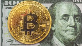 Un bitcoin y un billete de 100 dólares.