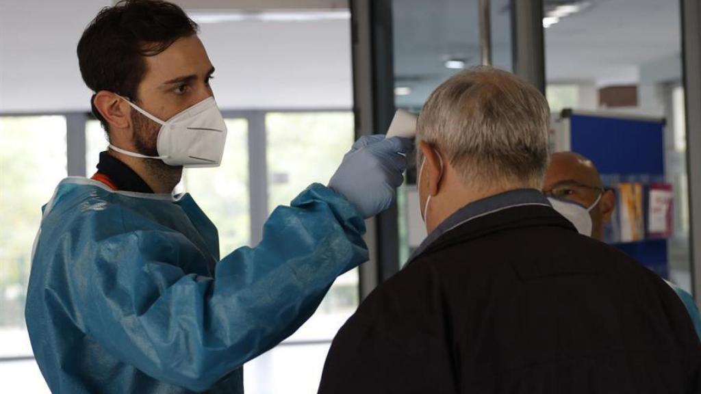 Personal sanitario toma la temperatura a una persona en la entrada de un centro.