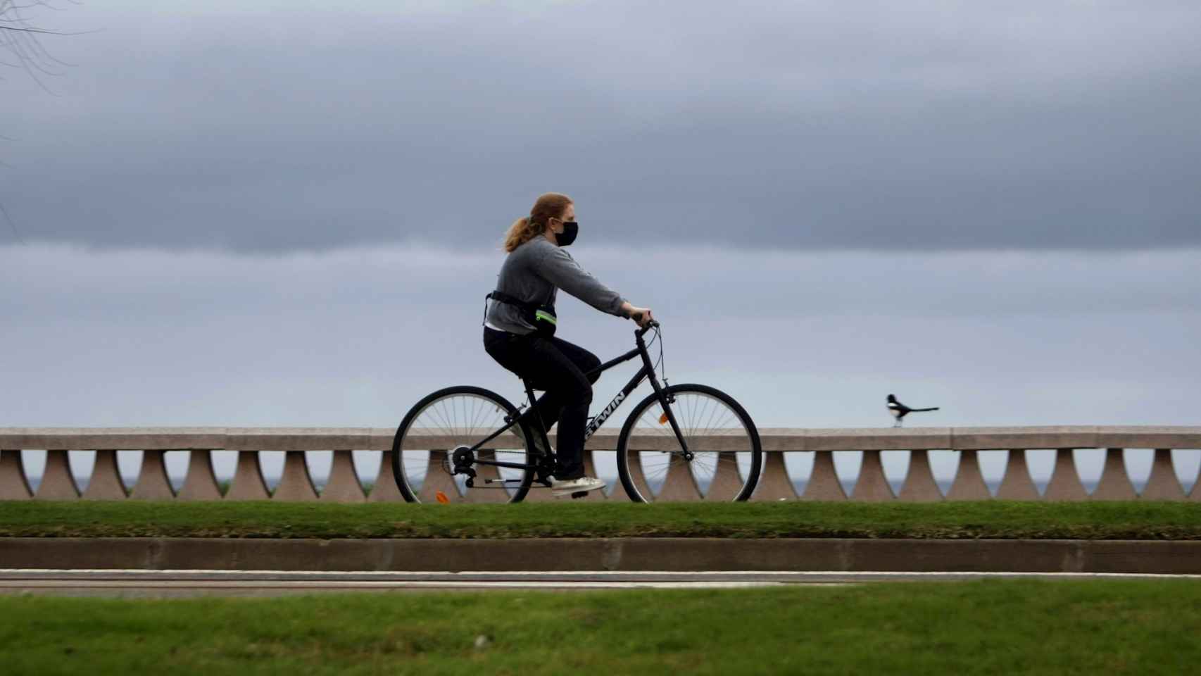 Una mujer monta en bicicleta portando una mascarilla en el paseo marítimo de La Coruña.