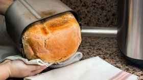 Una persona extrae el pan recién hecho en su panificadora.