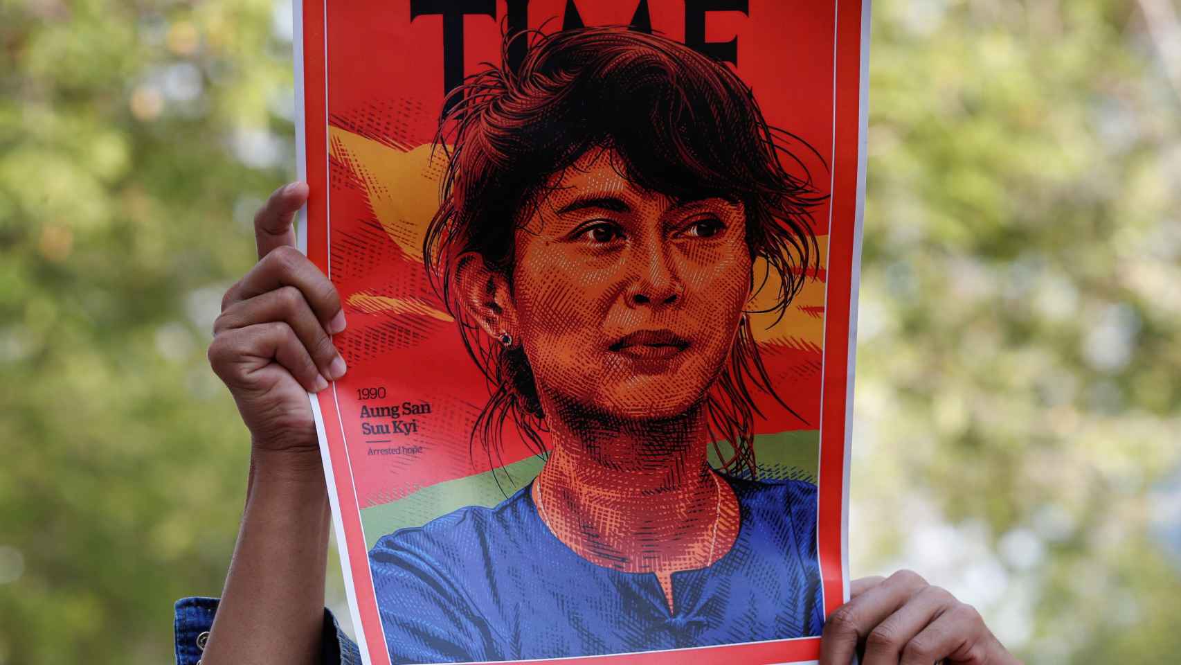 Un manifestante sujetando una pancarta con la cara de Aung San Suu Kyi.