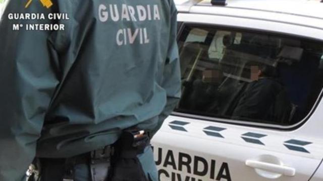 Un guardia civil delante de su vehículo.