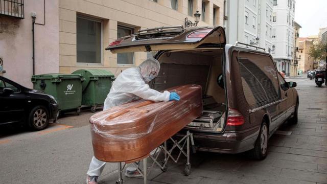 Un funerario metiendo un ataúd en un coche.