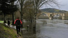 Varias personas caminan por una zona inundada por el río Miño, en Ourense.