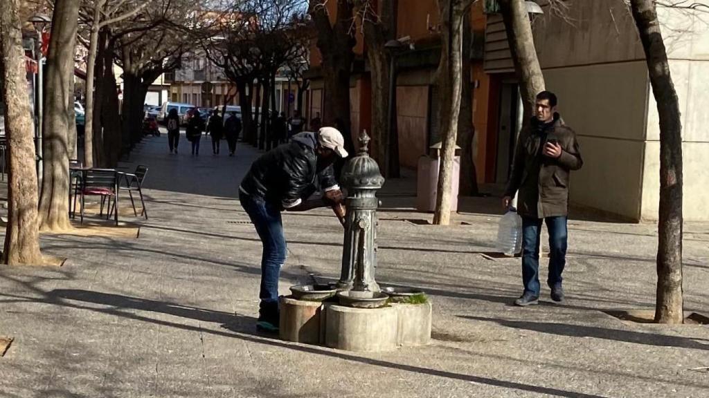 Un subsahariano se lava en una fuente pública