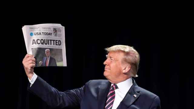 Donald Trump sostiene un ejemplar del periódico USA Today con la palabra absuelto.