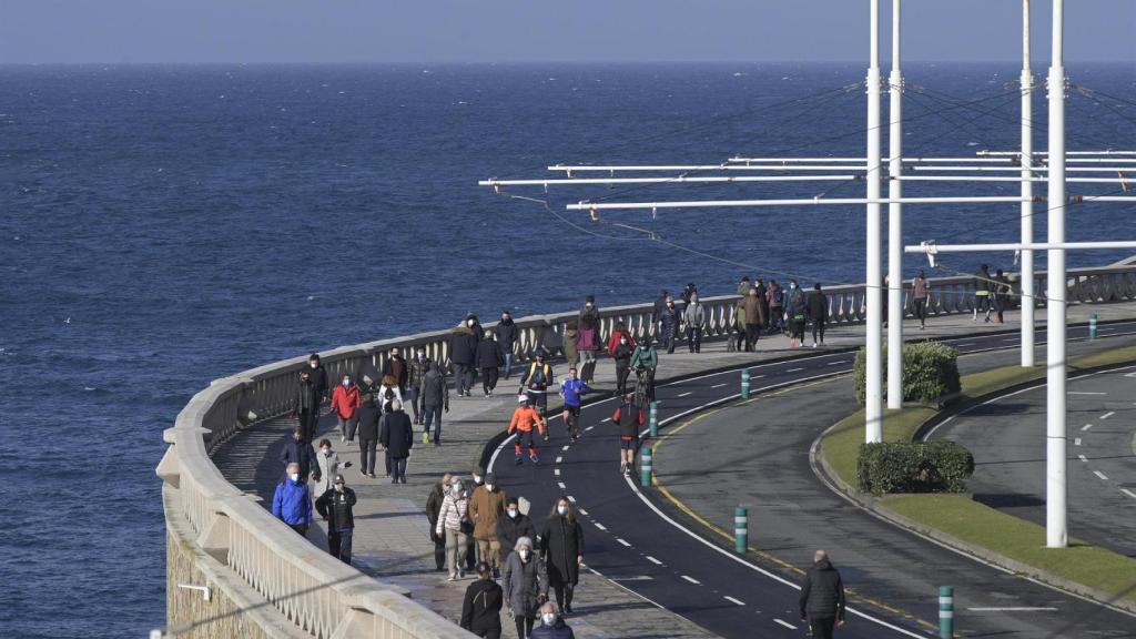 Varias personas caminan por el paseo marítimo en A Coruña.