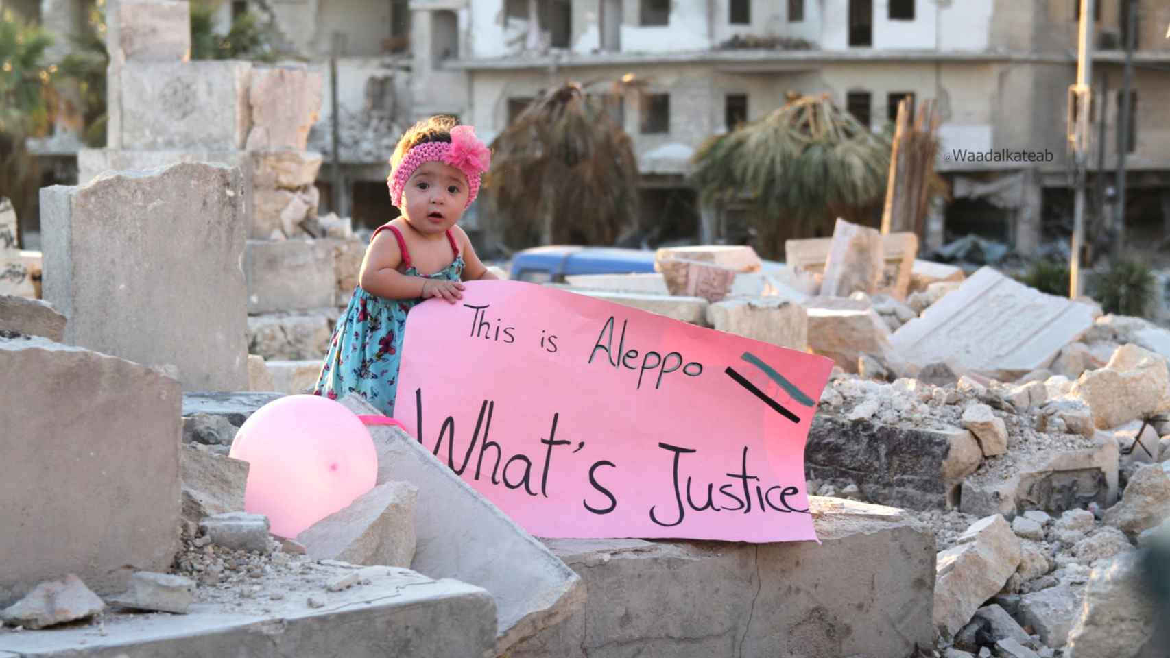 Sama sostiene un cartel entre las ruinas de Alepo.