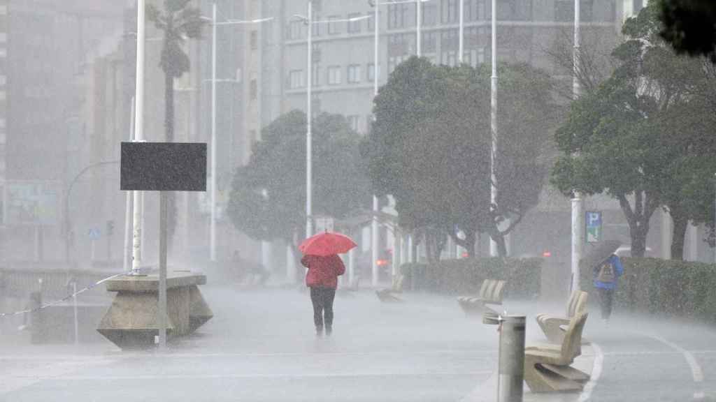 Una mujer bajo la lluvia en el Paseo Marítimo de A Coruña.