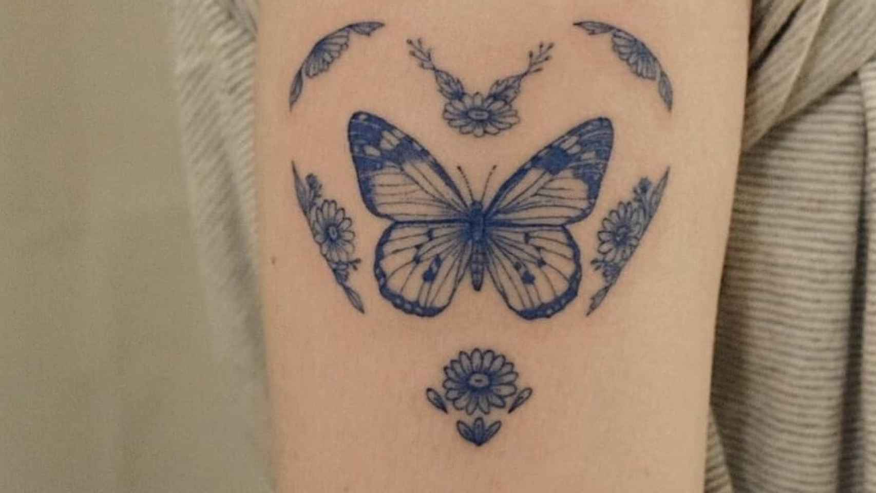 Mariposa tatuada en la parte superior del brazo.