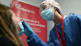 Una trabajadora sanitaria toma una muestra de saliva para un test de antígenos en la estación de Atocha en Madrid.