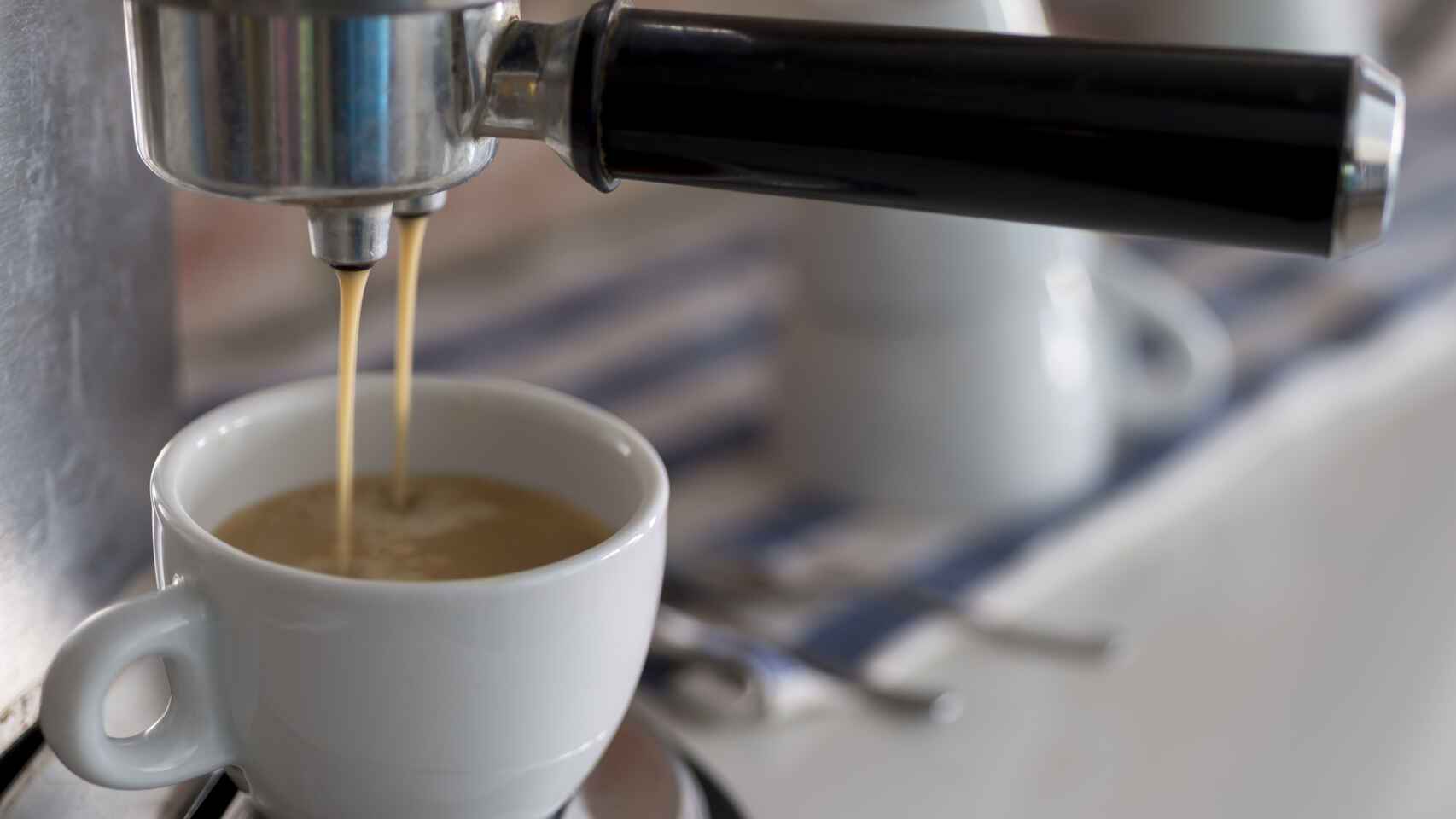 Una cafetera eléctrica echando el café en una taza.