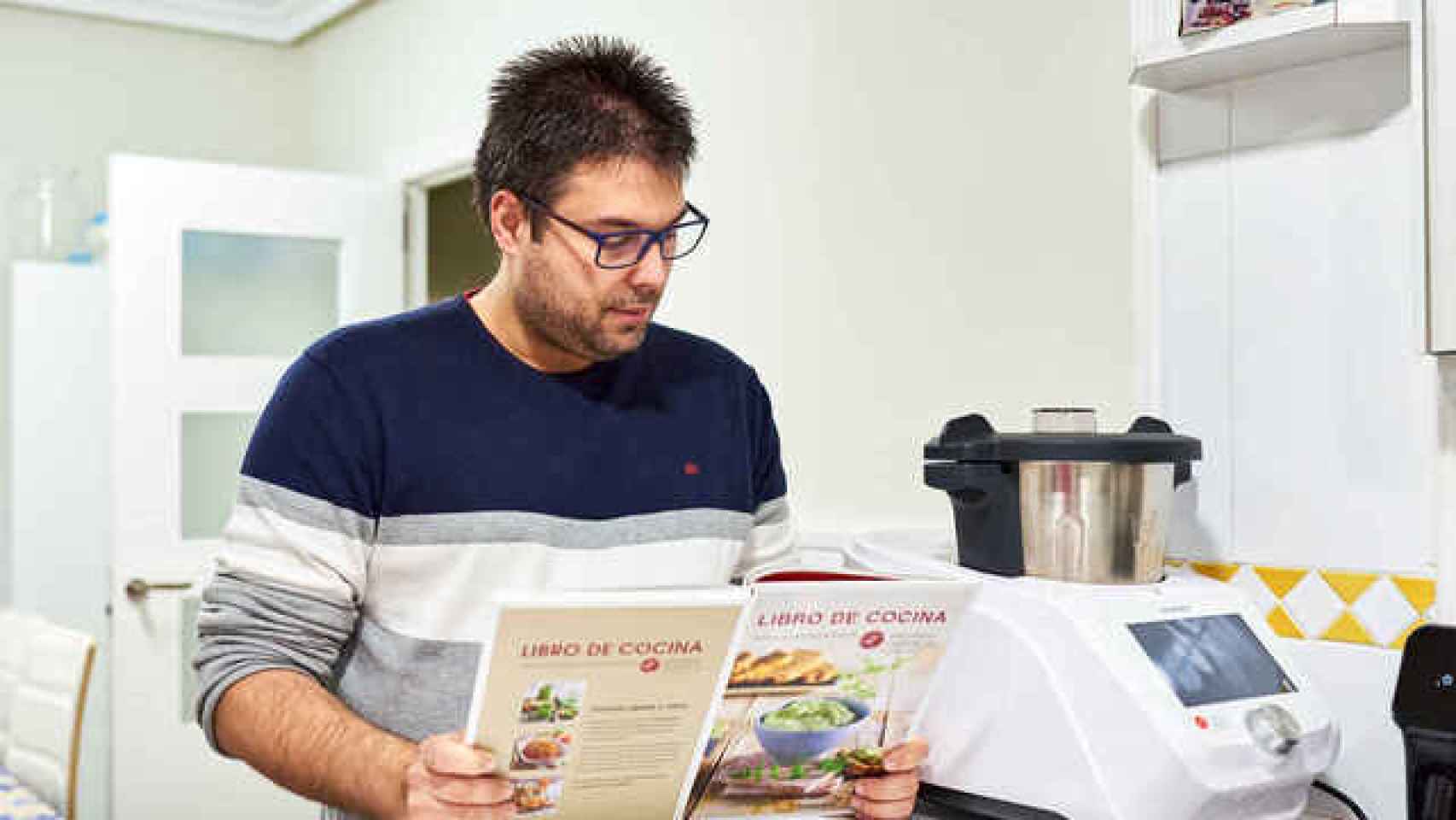 Un usuario leyendo un libro de recetas para su robot de cocina.