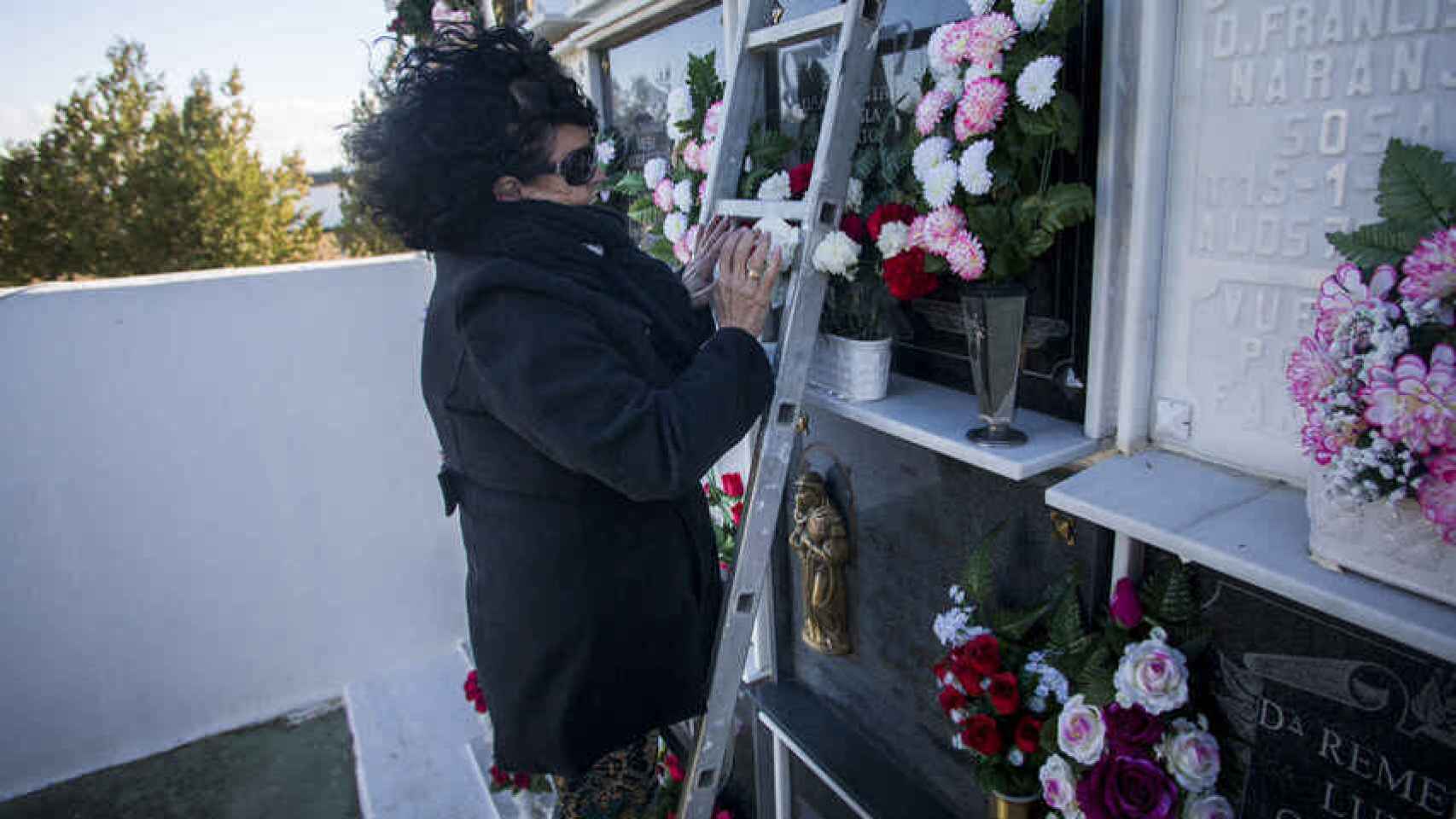 Sofía Benítez-Cubero poniendo flores a su tía Antonia Reguera, la persona que la crió, en el cementerio de El Coronil (Sevilla).