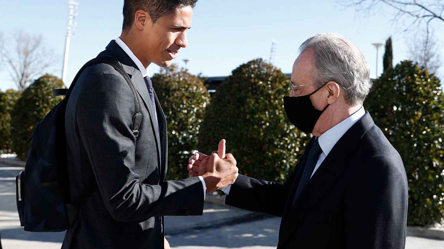 Raphael Varane se da la mano con Florentino Pérez antes de viajar a Bérgamo