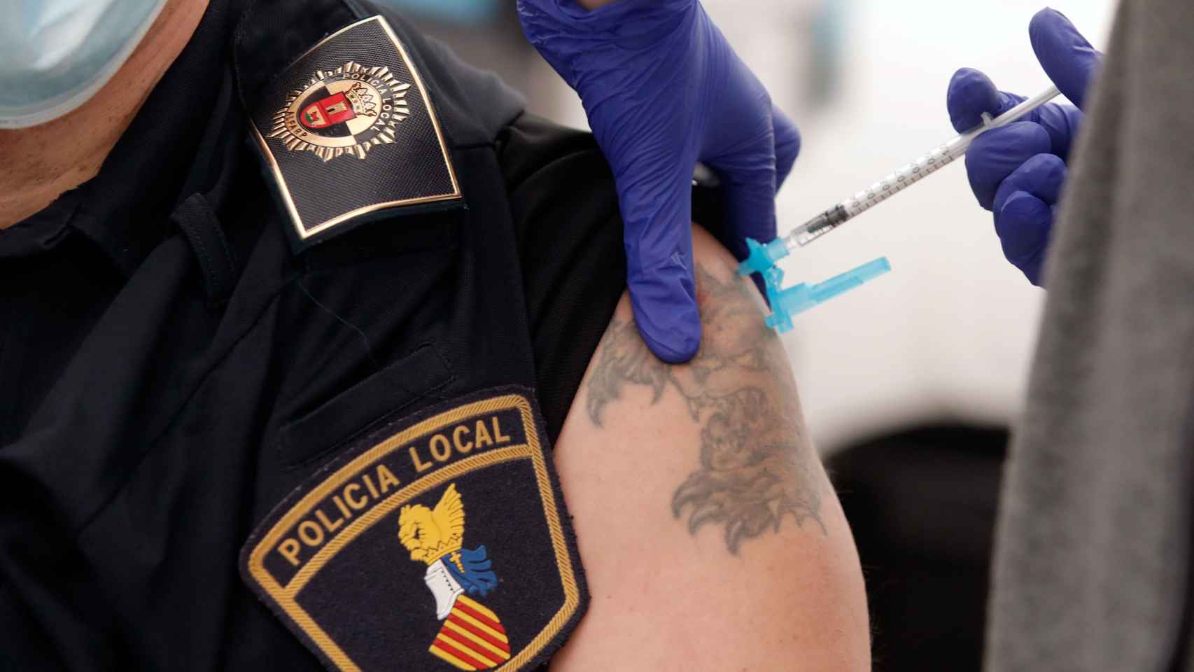 Un sanitario vacuna contra la Covid-19 a un policía local en la Comunidad Valenciana.