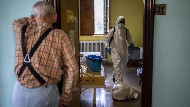 Un anciano contempla en una residencia la actuación del personal sanitario.