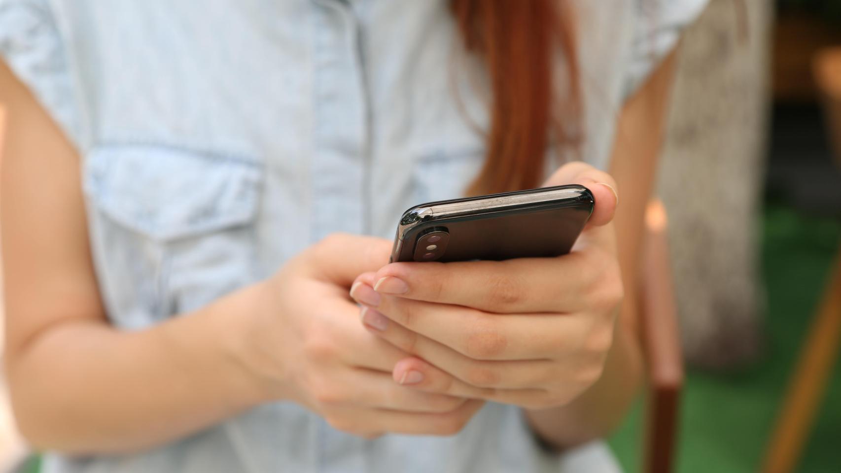 Una joven contempla una aplicación en su smartphone.