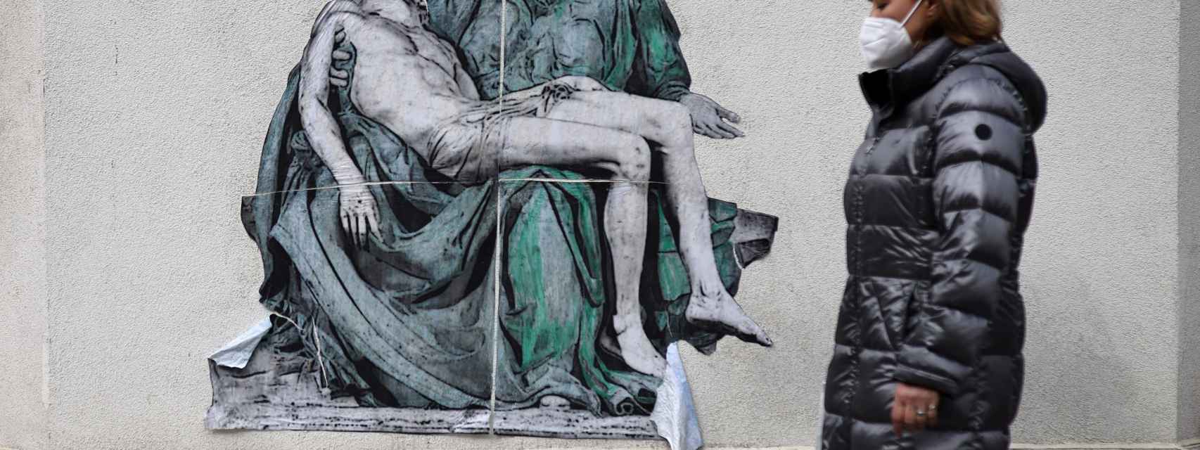Una mujer con mascarilla pasea ante un mural sobre la Covid en Sofía, Bulgaria.